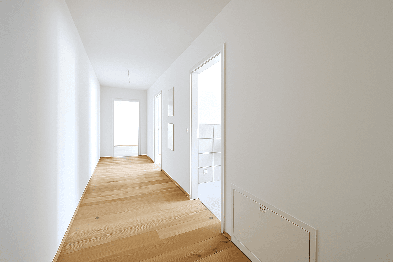 Heller, moderner Flur mit Holzboden und weißen Wänden, der zu weiteren Räumen führt.