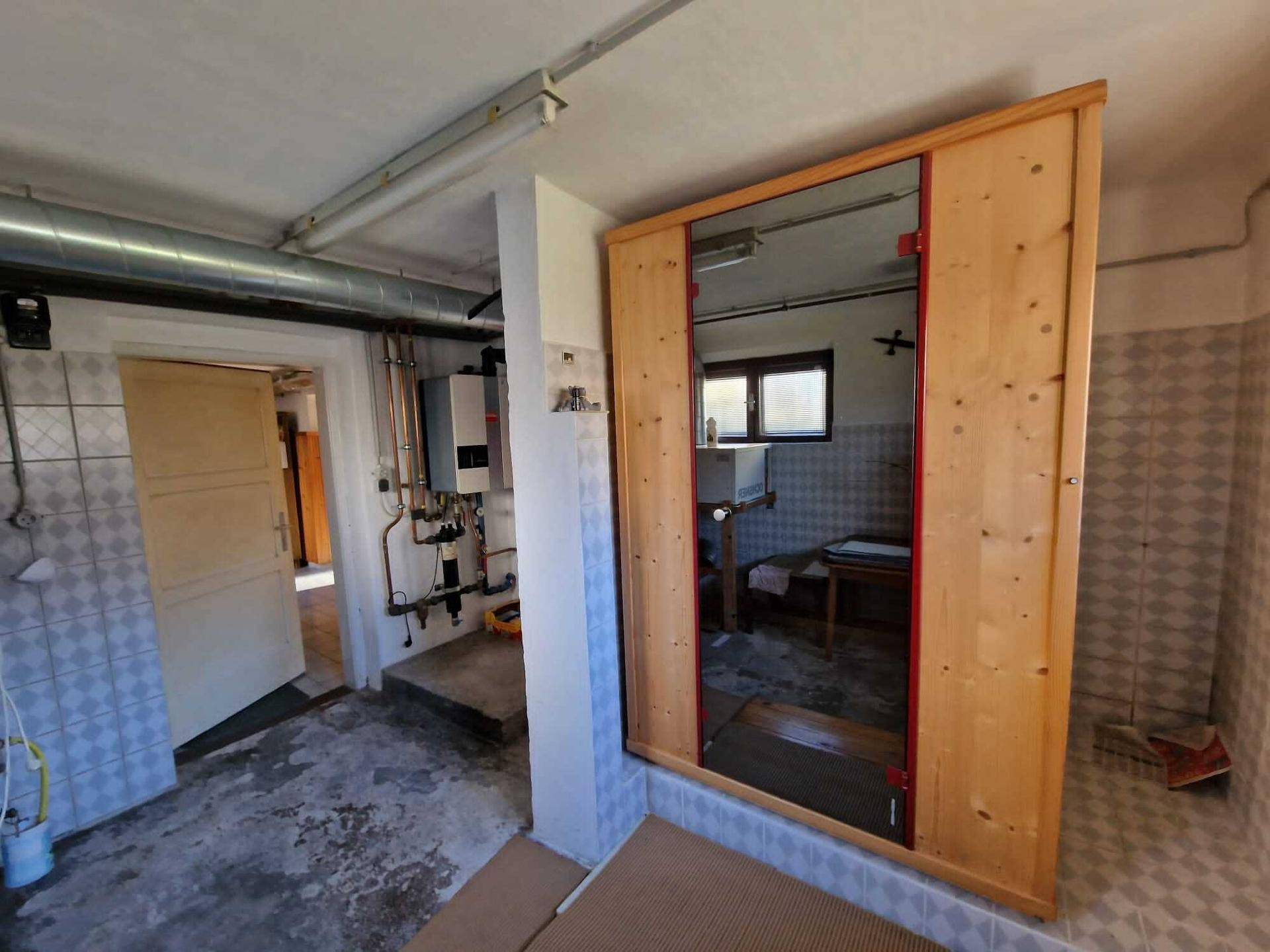 Hauswirtschaftsraum im Keller mit einer sichtbaren Sauna und Heizungsinstallationen.