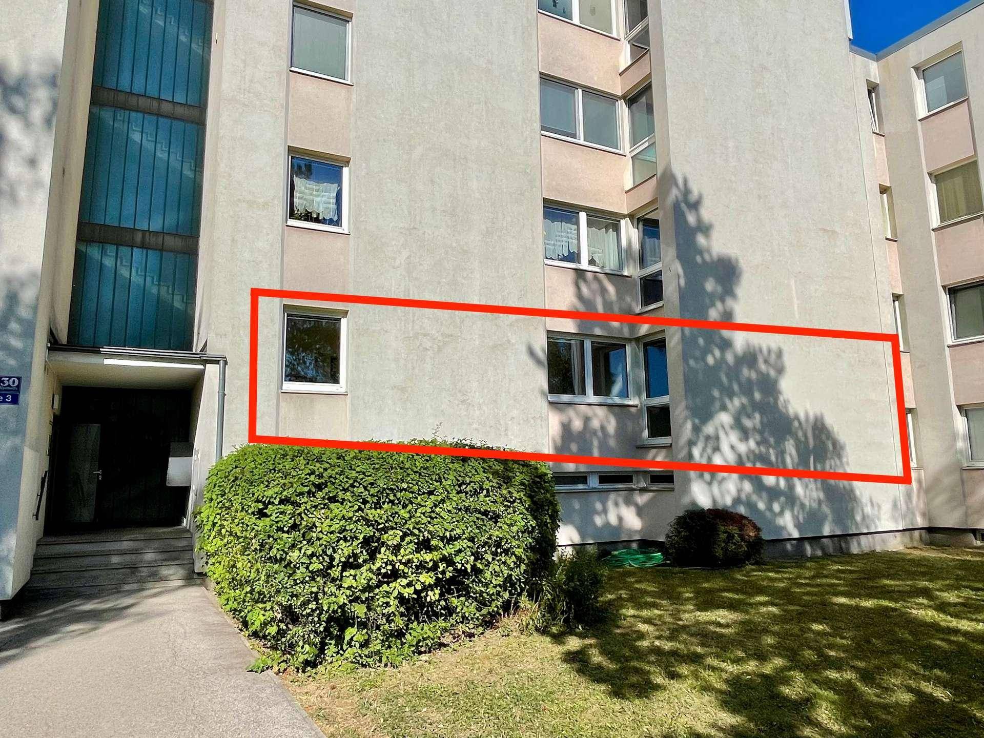 Außenansicht eines Mehrfamilienhauses mit grüner Bepflanzung im Vordergrund.