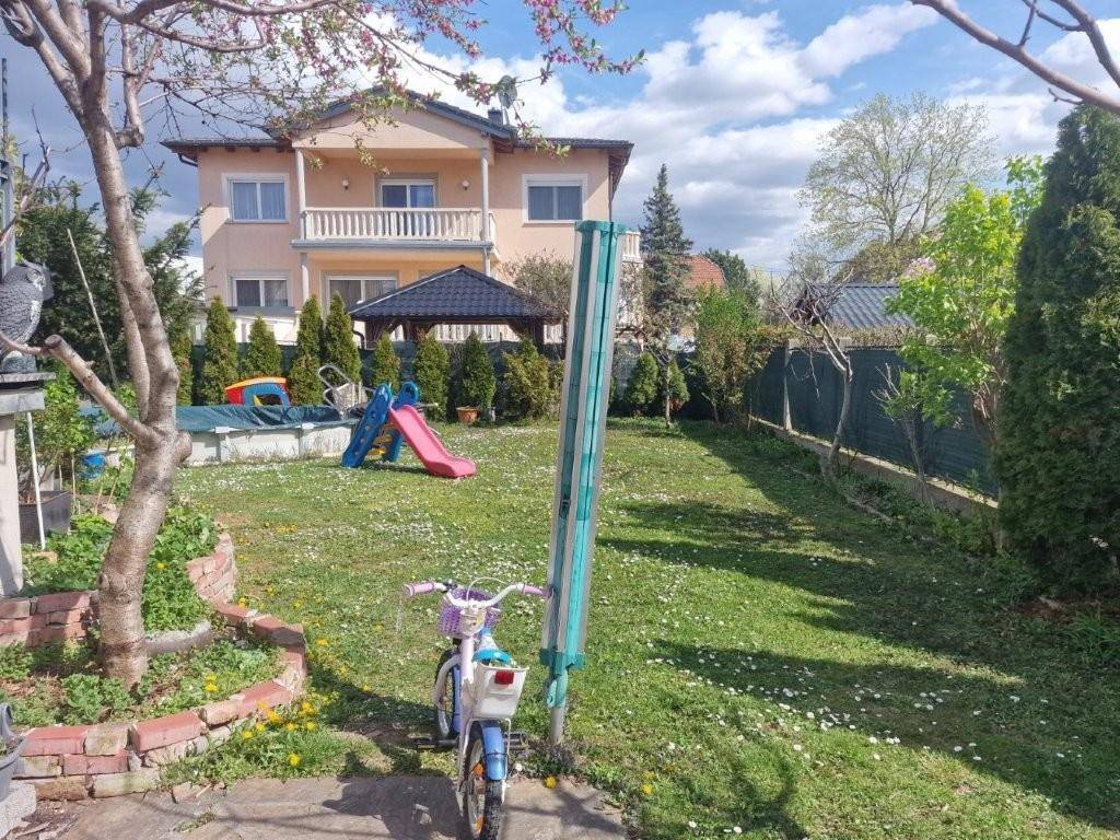 Großer Garten mit Rasenfläche, kleinem Pool und Kinderspielgeräten.