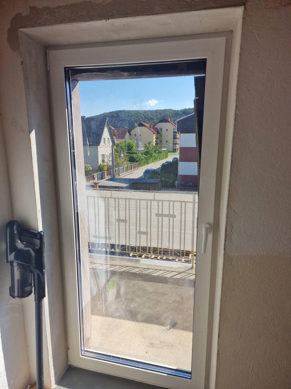 Fenster mit weitem Blick auf die umliegende Wohngegend und Hügellandschaft.