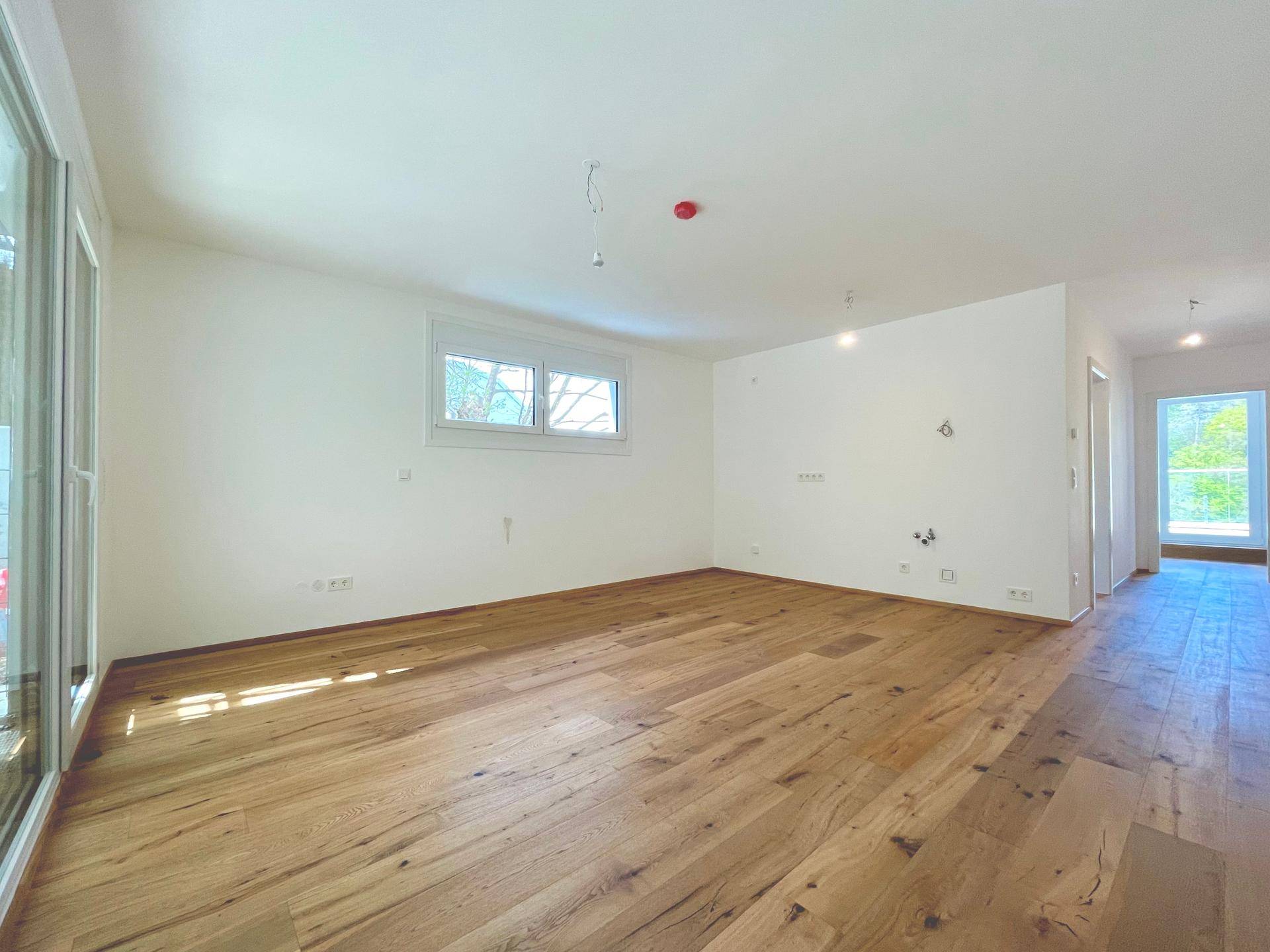 Geräumiges Wohnzimmer mit hellem Holzboden und weiß gestrichenen Wänden, bereit zur individuellen Gestaltung.