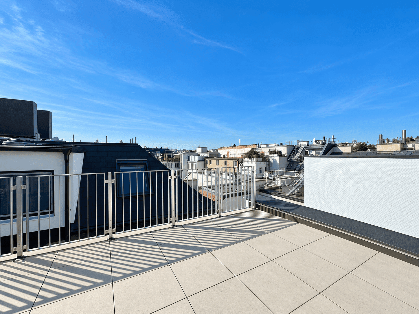 Geräumige Dachterrasse mit Fliesenboden und Panoramablick über die umliegenden Dächer.