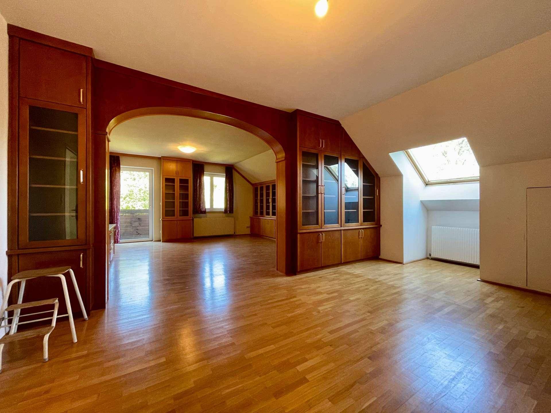 Geräumiger Wohnbereich im Dachgeschoss mit Holzboden, Einbauschränken und Dachfenster.
