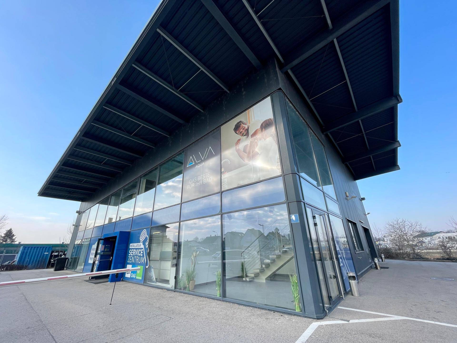 Modernes Geschäftsgebäude mit markanter Glasfassade und großem Dachüberstand, einladend und funktional.