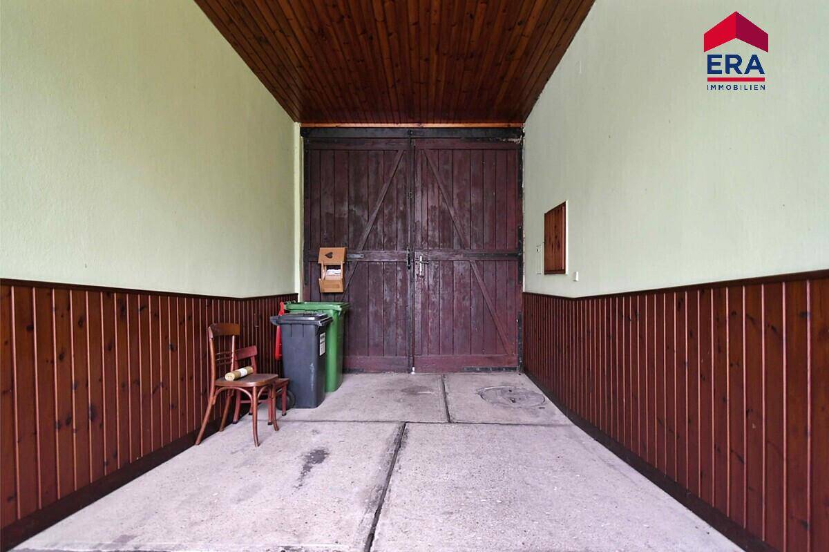 Geräumige Garage oder Abstellraum mit Holzwänden und Betonelementen am Boden.