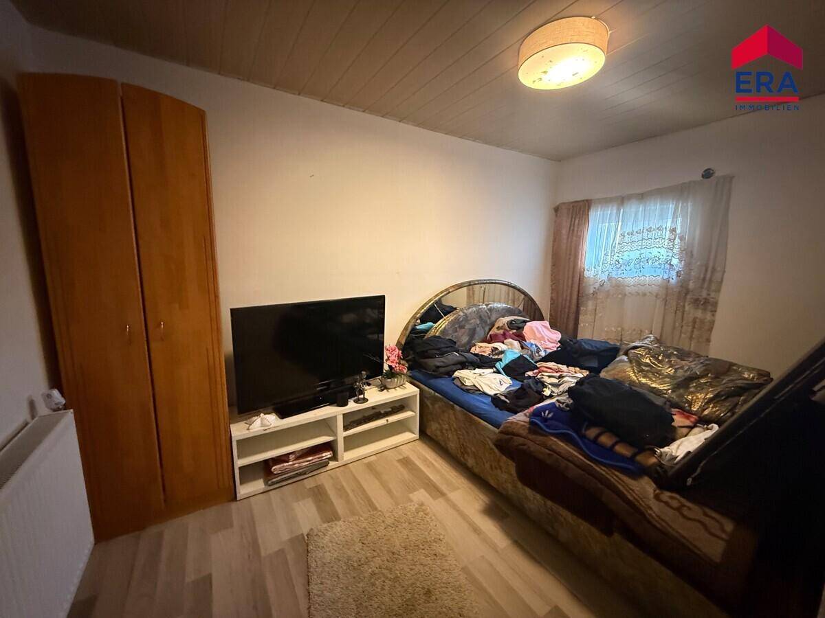 Gemütliches Schlafzimmer mit Holzbett, Kleiderschrank und Holzdeckenverkleidung.