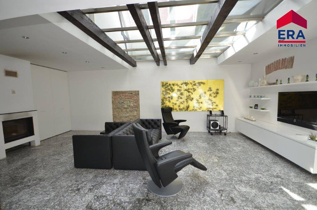 Großzügiges Wohnzimmer mit modernem Interieur, Kamin und beeindruckender Glasdachkonstruktion.