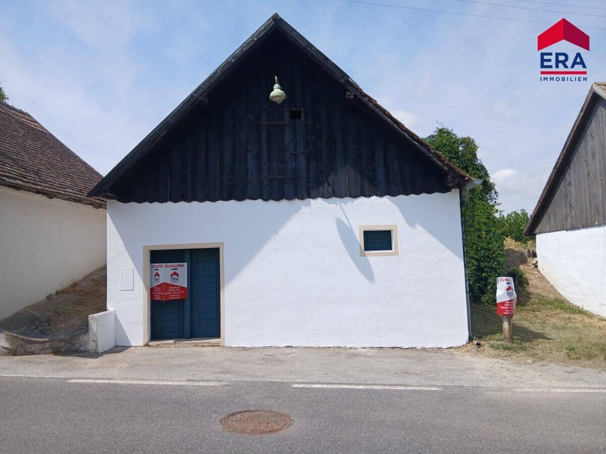 Ansicht des ländlichen Gebäudes mit weiß getünchter Fassade und traditionellem Holzdachgiebel.