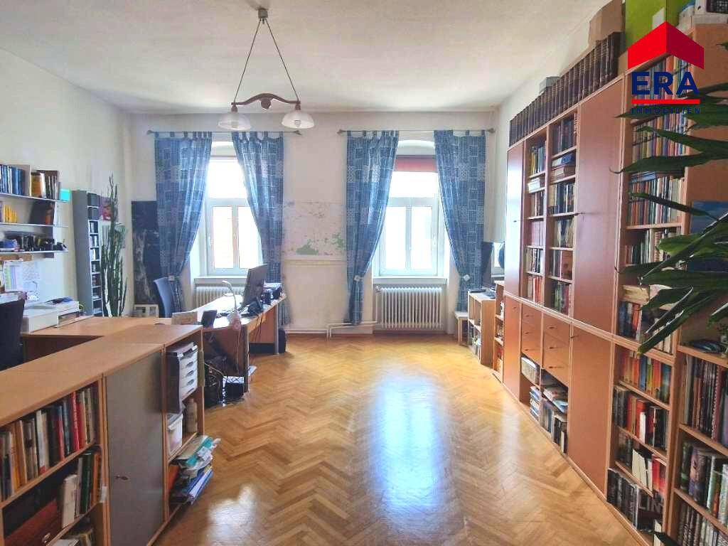 Geräumiges Arbeitszimmer mit Fischgrätparkett, Bücherregalen und zwei großen Fenstern.