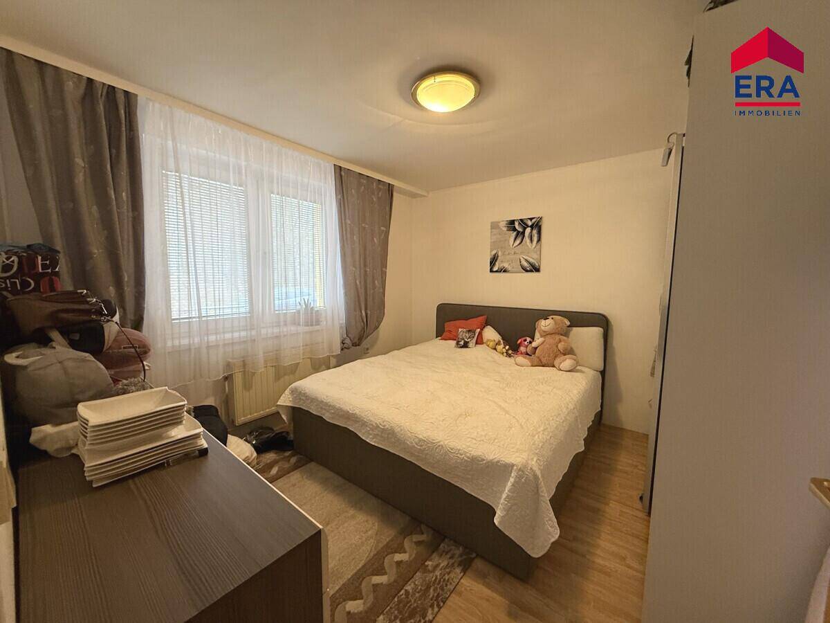 Weiteres Schlafzimmer mit Doppelbett, Kommode und einem Fenster mit Jalousien.