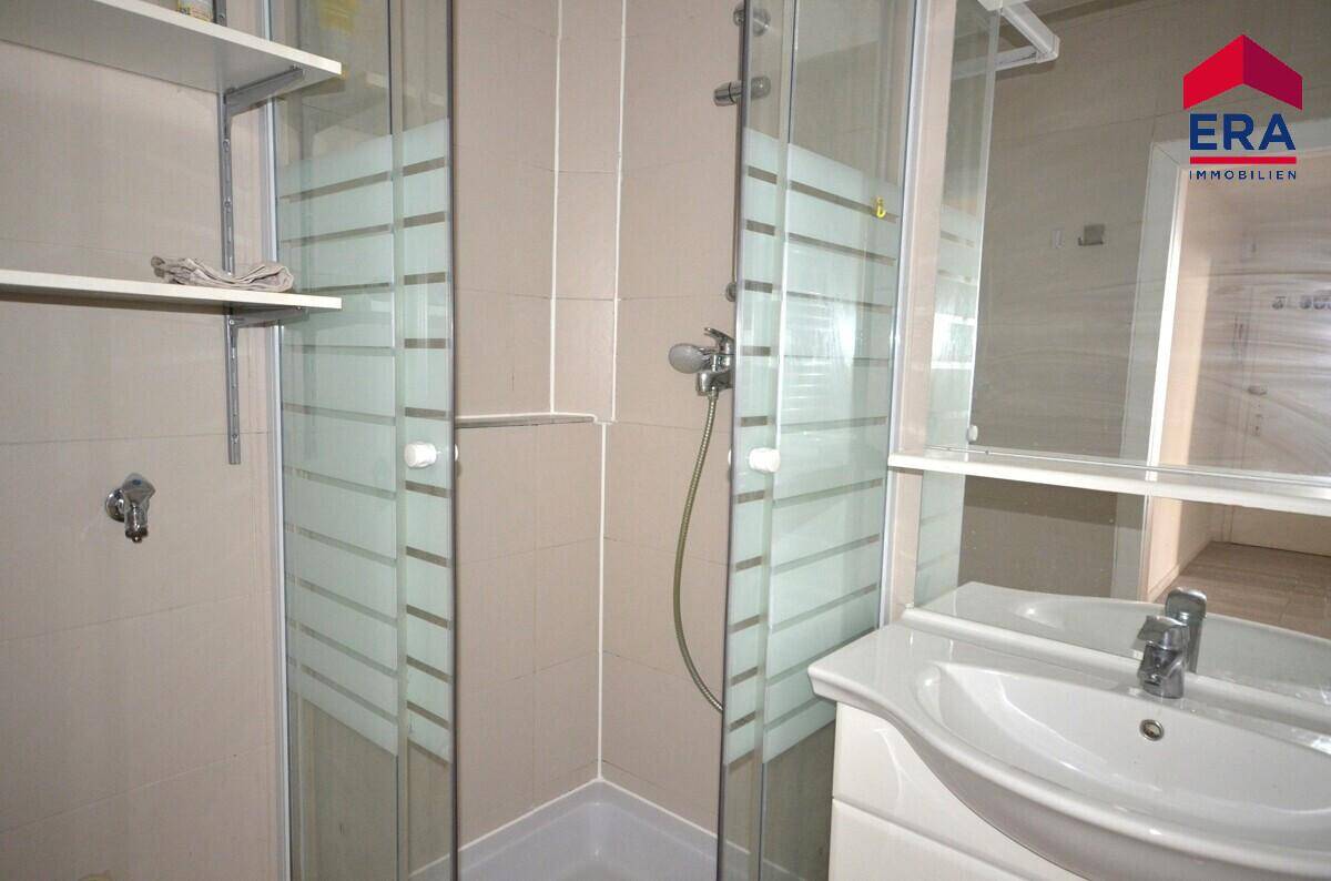 Modernes Badezimmer mit Eckduschkabine, Waschbecken und hellen Fliesen, in gutem Zustand.