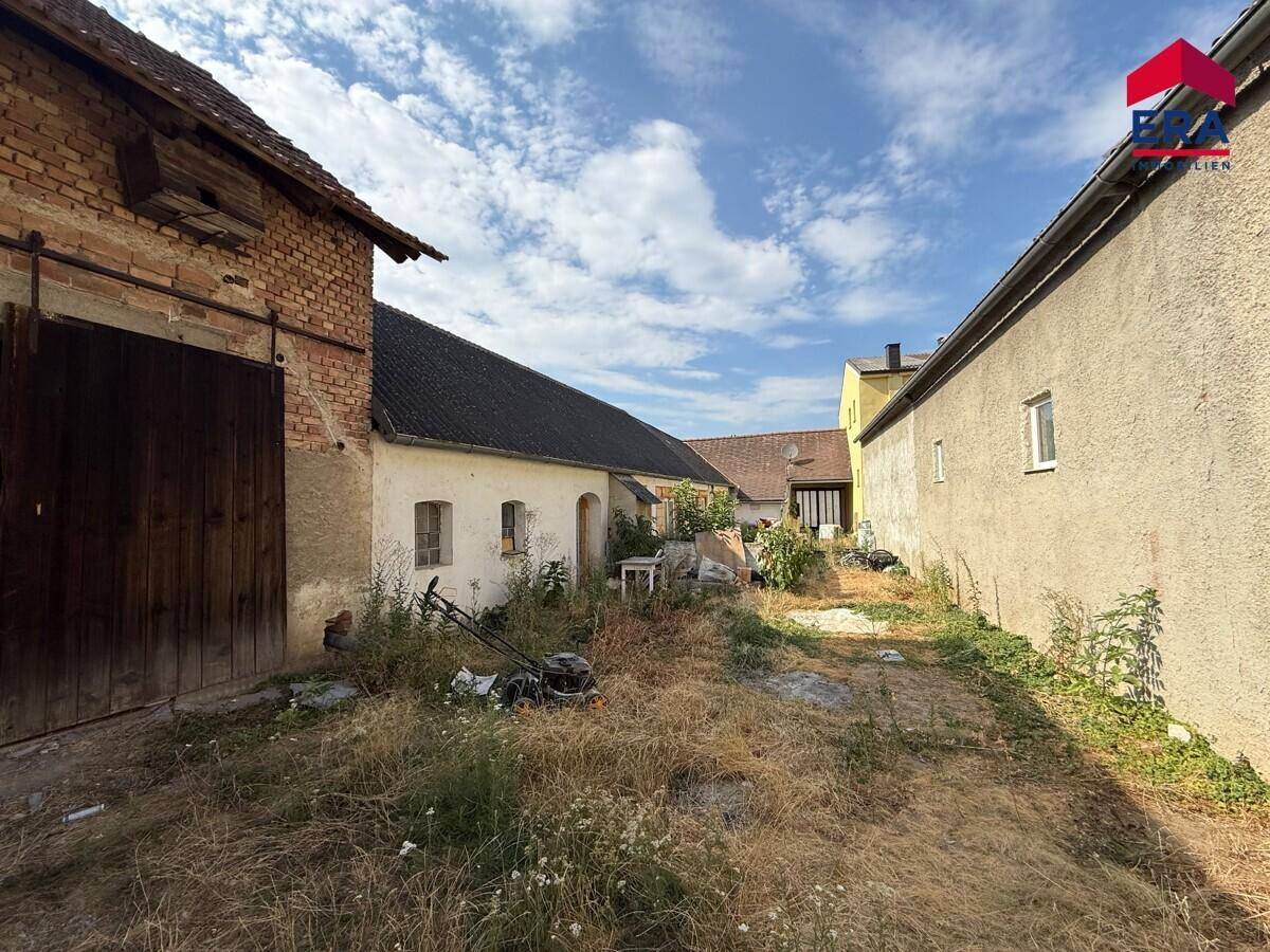 Hinterhof oder Gartenbereich zwischen Gebäuden mit viel Grün und ungenutzter Fläche.