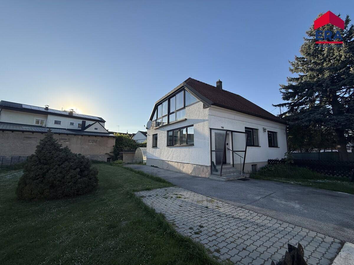 Freistehendes Haus mit gepflegtem Vorgarten und Zufahrt, umgeben von viel Grün.