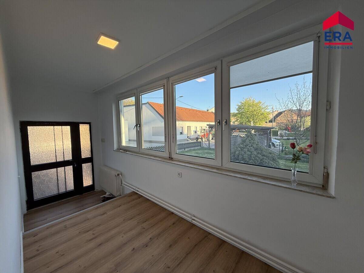 Heller Eingangsbereich oder Flur mit Holzfußboden und großen Fenstern.