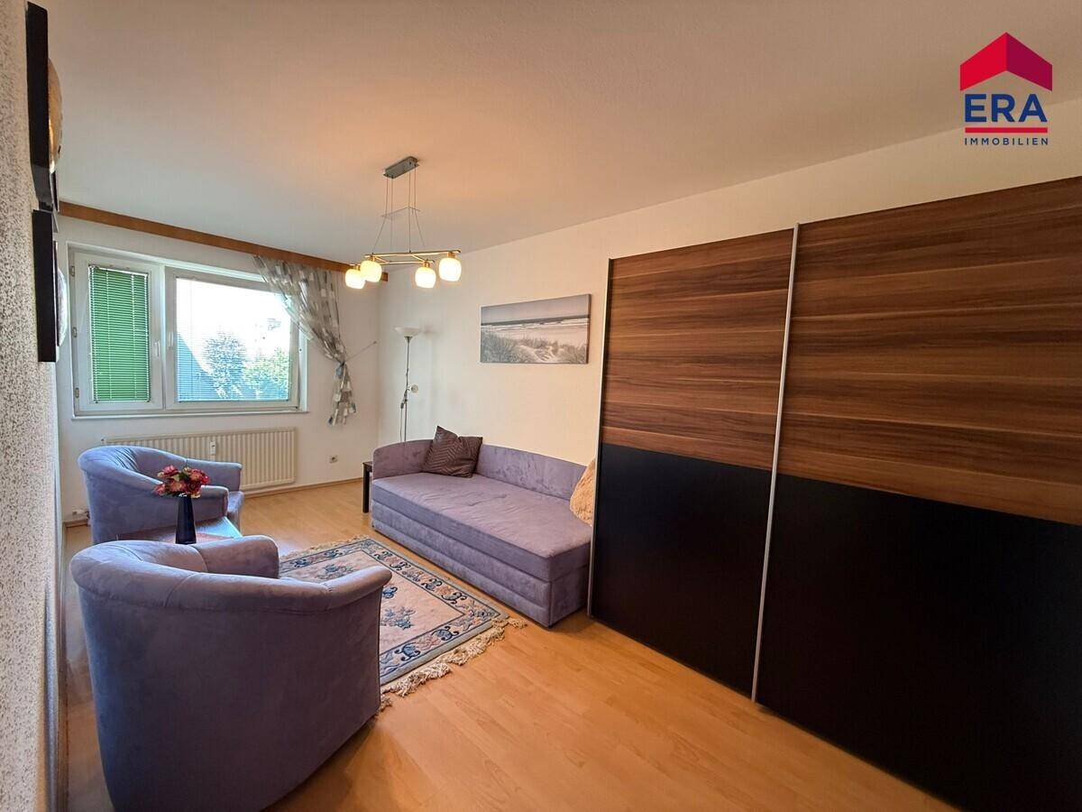 Schlafzimmer mit Schlafsofa, Holzfußboden und großem Einbauschrank.