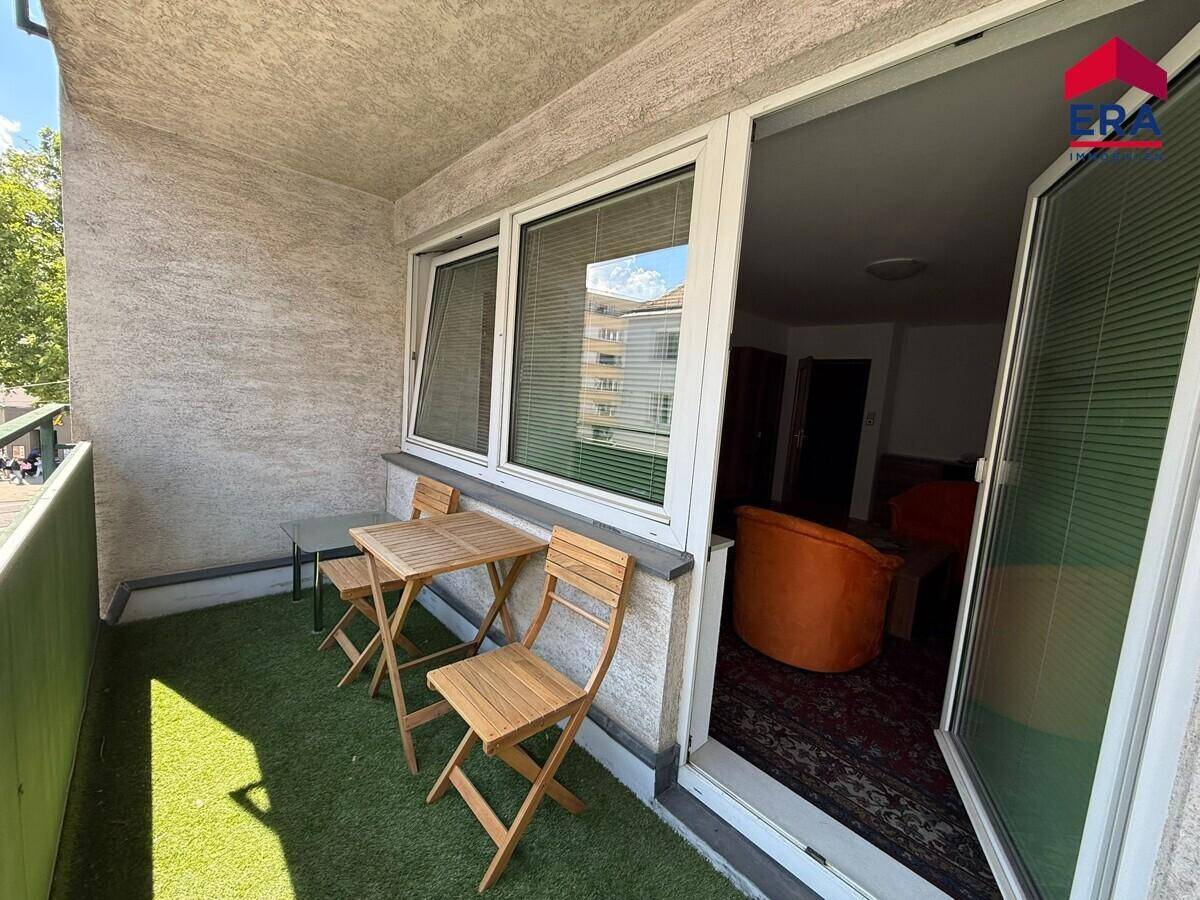 Kleiner Balkon mit Kunstrasen und Holztisch, zugänglich vom Innenbereich.