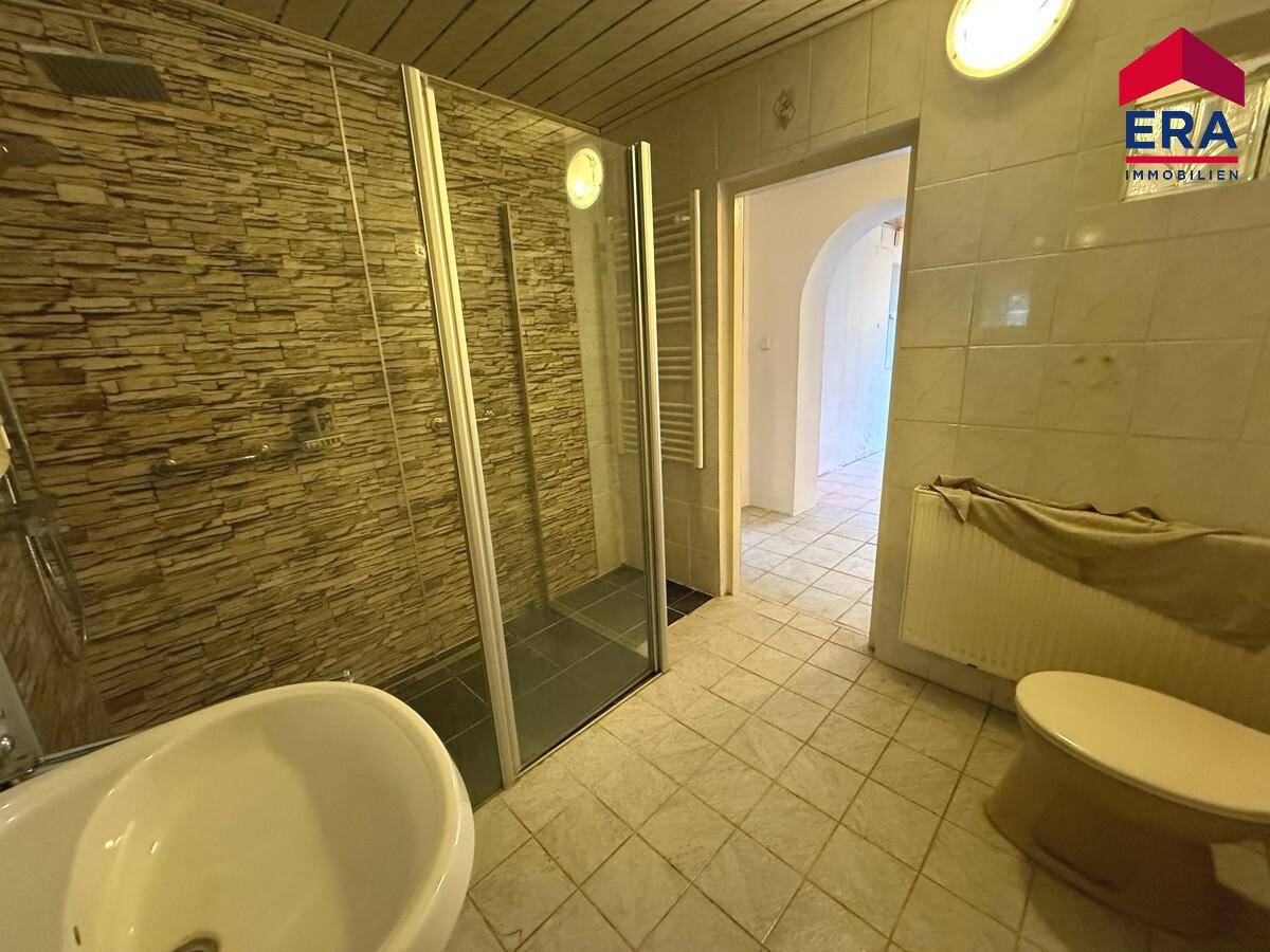 Badezimmer mit Duschkabine und gefliesten Wänden, bietet funktionale Ausstattung.