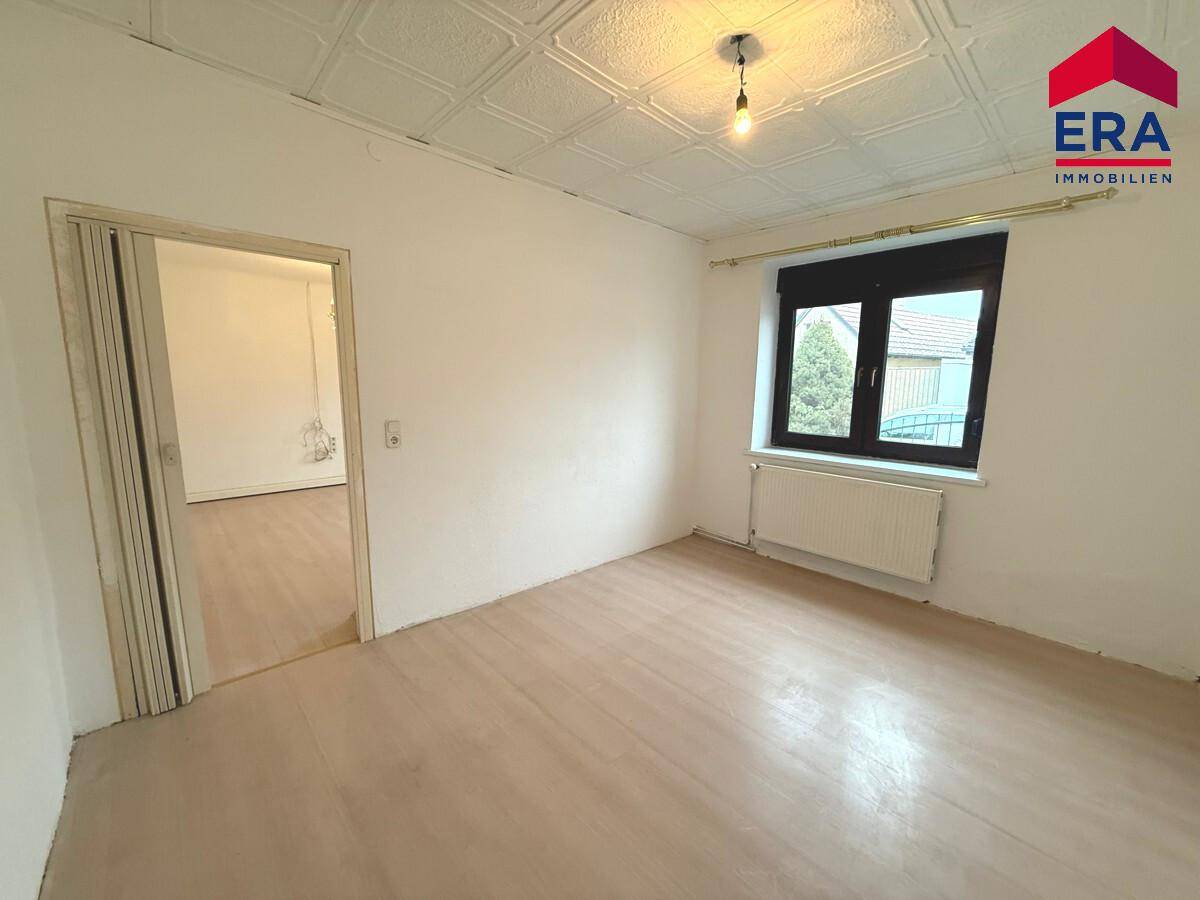 Heller Raum mit Laminatboden und strukturiertem Deckenmuster, ideal für Schlaf- oder Wohnbereich.