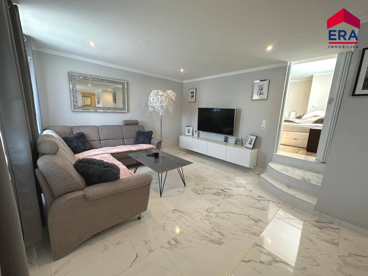 Gemütlicher Wohnbereich mit Sofa, Fernseher und Zugang zu einem erhöhten Schlafzimmer.