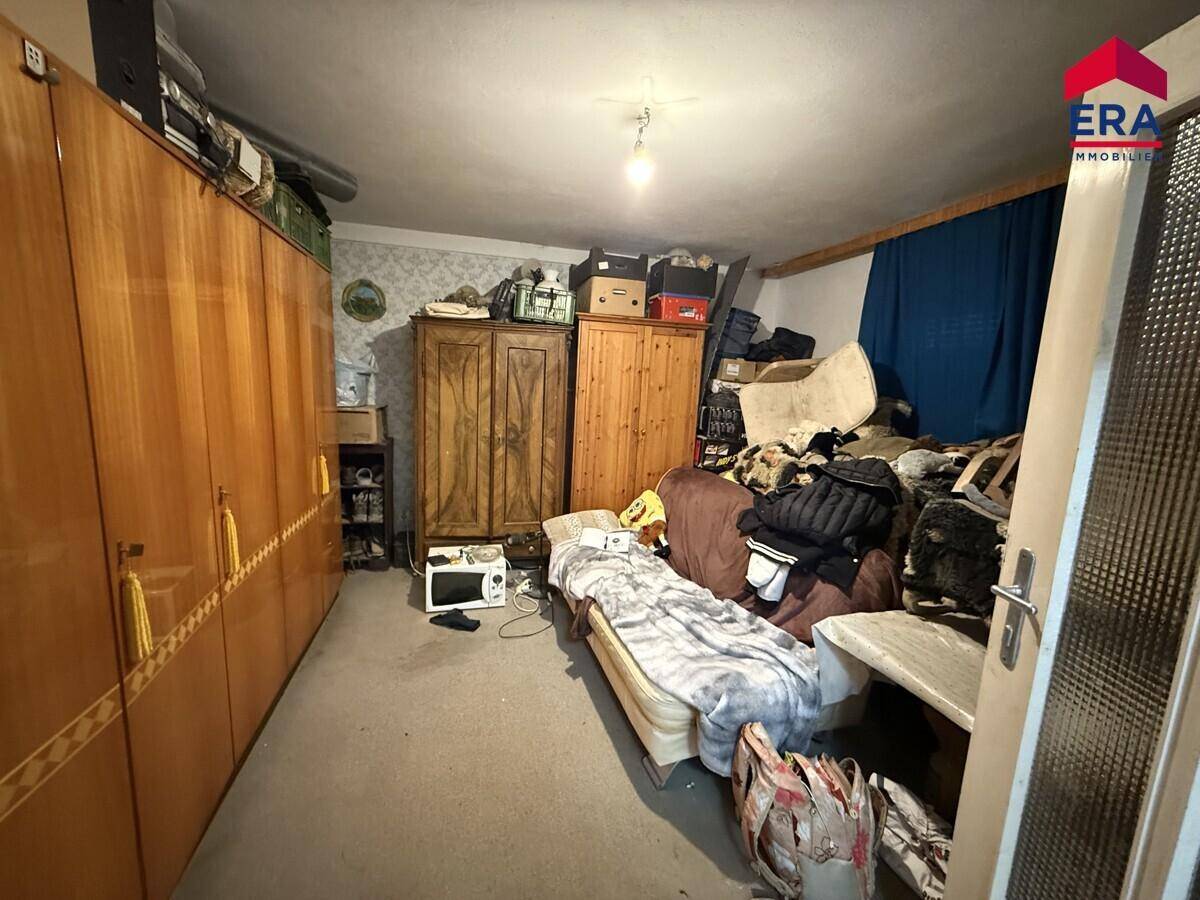 Schlafzimmer mit Holzschränken, einem Bett und vielen persönlichen Gegenständen, die den Raum füllen.
