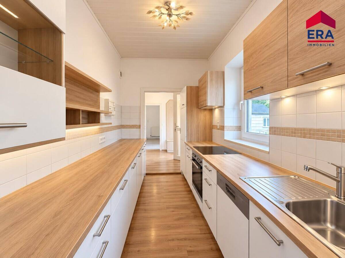 Moderne Küche mit Holz-Arbeitsplatten, weißen Schränken und integrierten Geräten, bereit zum Kochen.