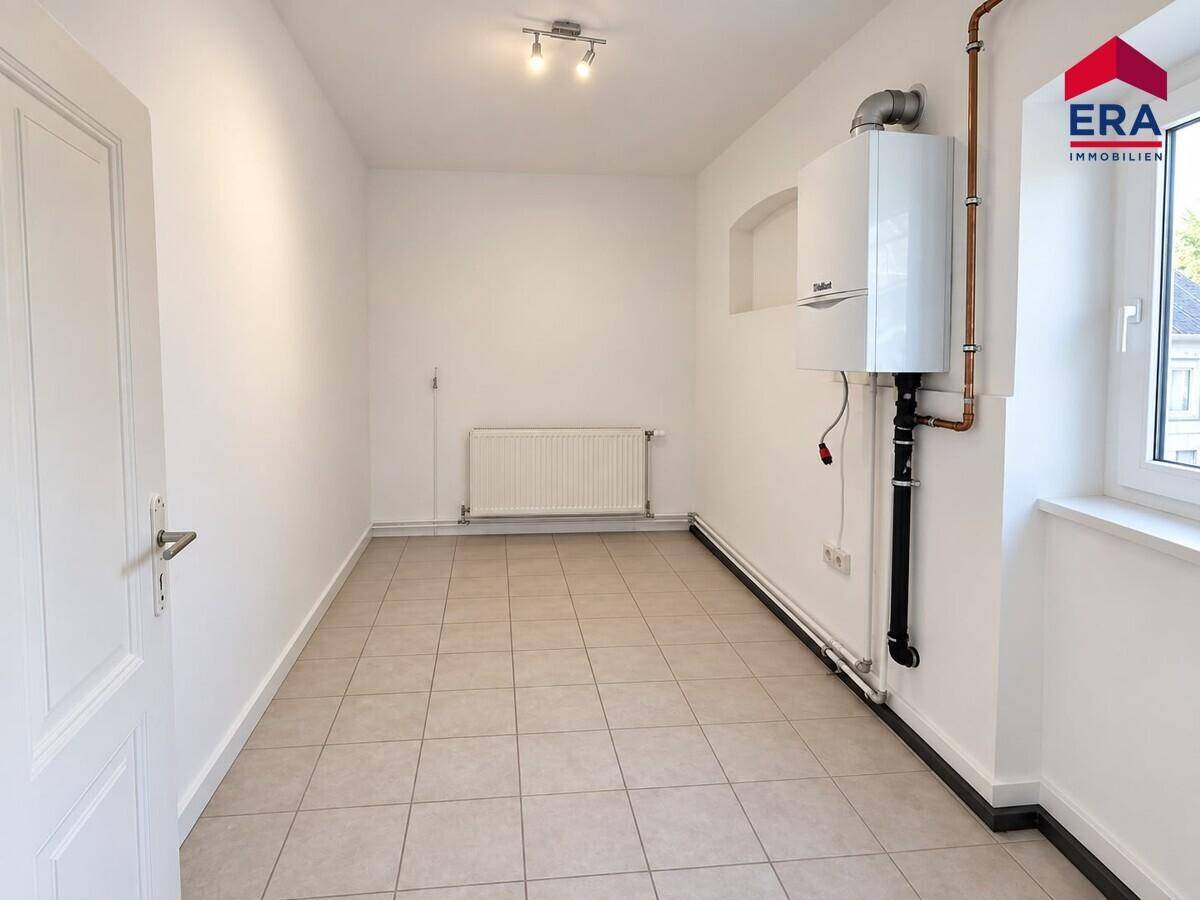 Praktischer Hauswirtschaftsraum mit Heizungsanlage und Fliesenboden, ideal für Technik und Lagerung.