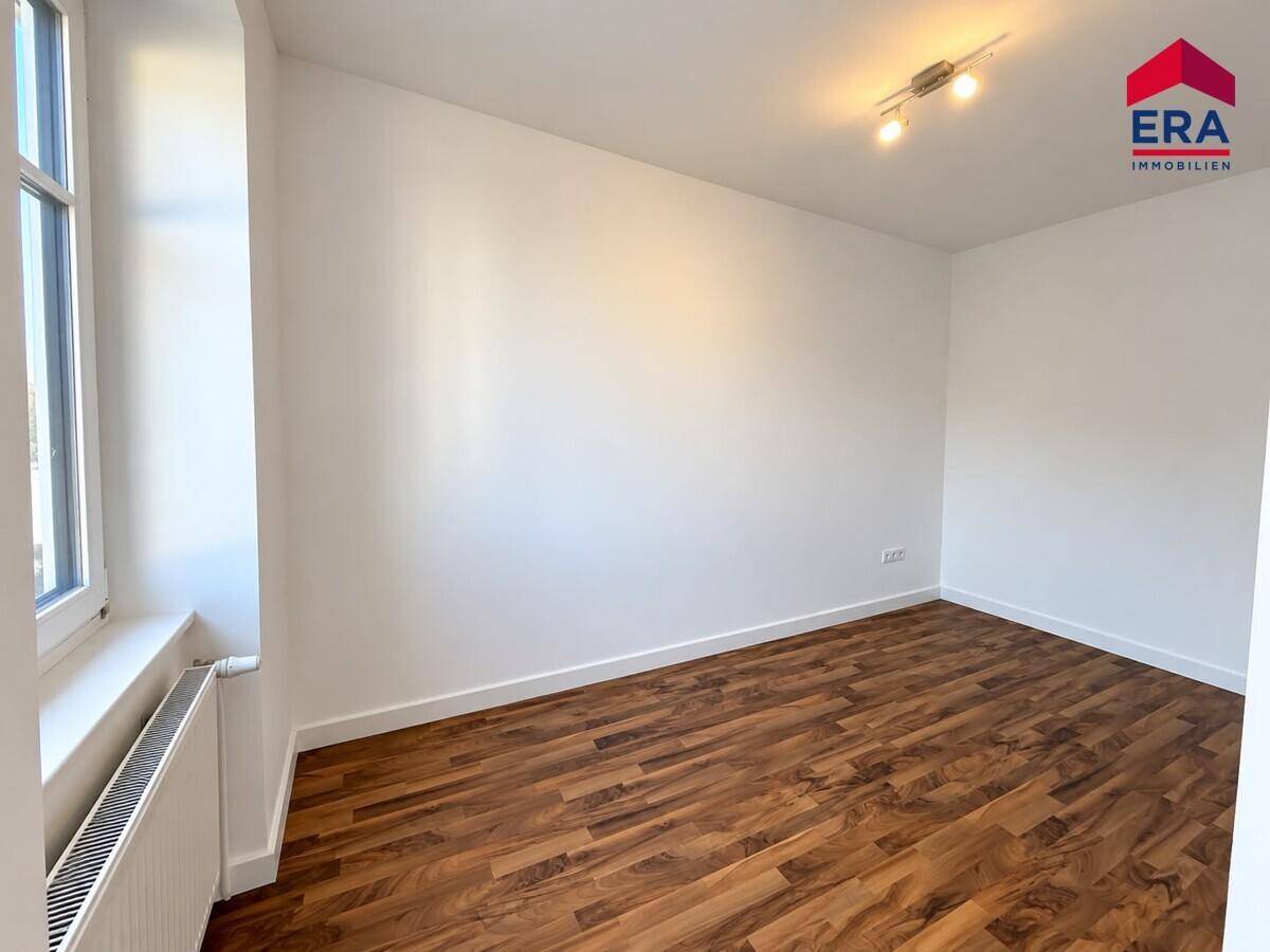 Leeres Zimmer mit Laminatboden und einem Fenster, bietet viel Potenzial für individuelle Einrichtung.