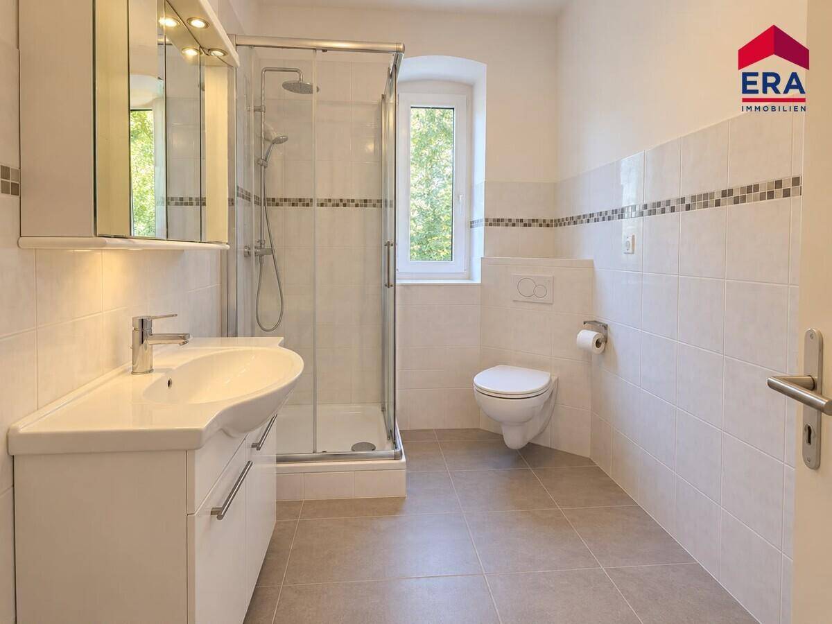 Helles Badezimmer mit Dusche, WC und Fenster, ausgestattet mit modernen Fliesen und Armaturen.