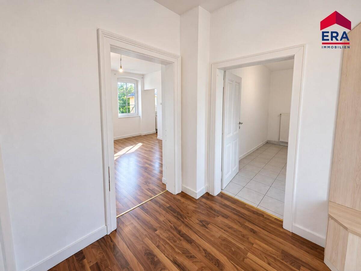 Heller Flur mit Laminatboden und Zugang zu mehreren Zimmern, bietet eine gute Raumaufteilung.