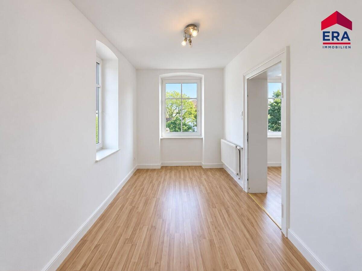 Helles Zimmer mit Laminatboden und zwei Fenstern, ideal als Schlaf- oder Arbeitszimmer nutzbar.