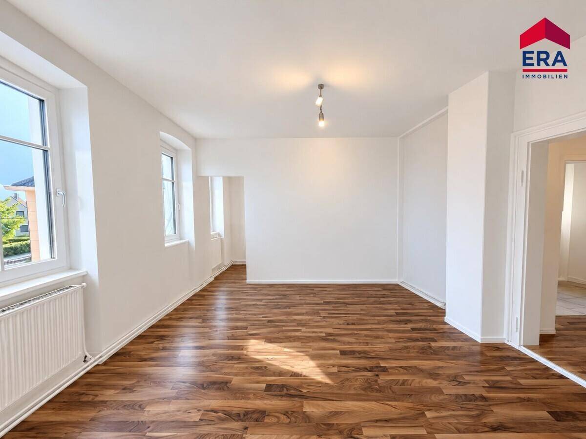 Geräumiges, unmöbliertes Zimmer mit Laminatboden und hellen Wänden, ideal für Wohnzwecke.