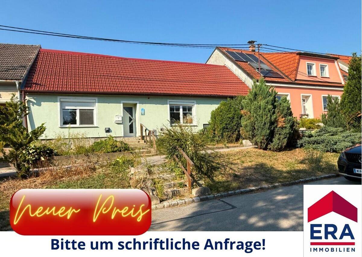 Einfamilienhaus mit rotem Ziegeldach und hellgrüner Fassade, umgeben von einem ungepflegten Vorgarten.