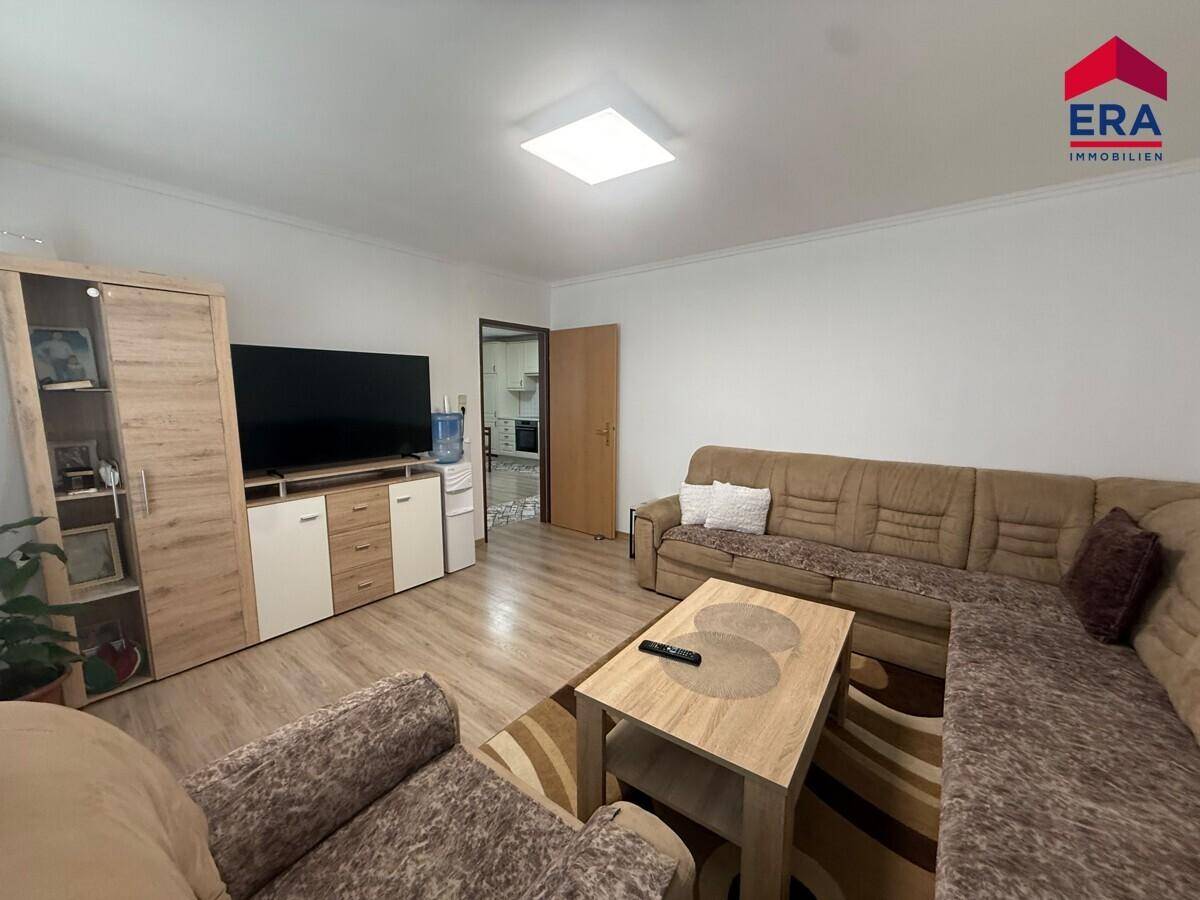 Gemütliches Wohnzimmer mit großem Sofa, Fernsehmöbeln und hellem Laminatboden.