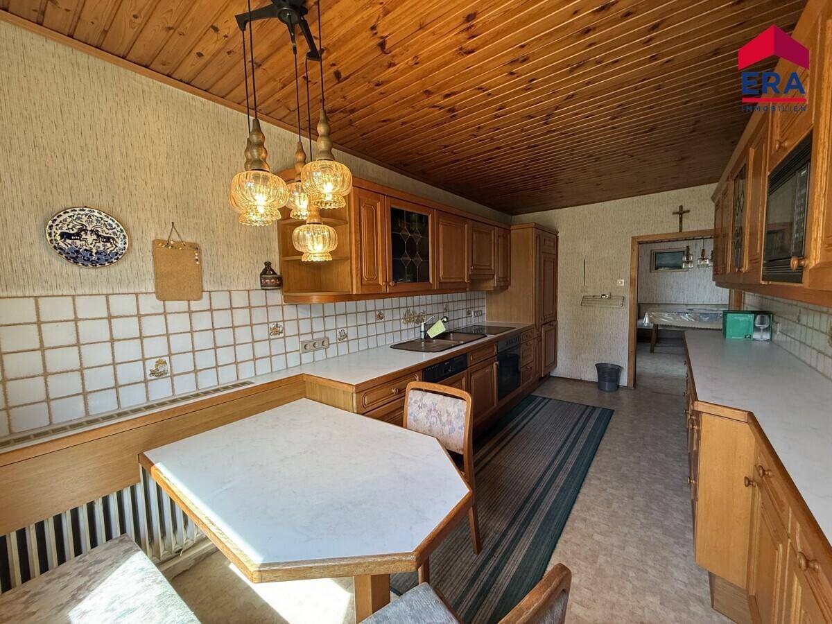 Traditionelle Küche mit Holzschränken, gefliestem Spritzschutz und einem gemütlichen Essbereich.