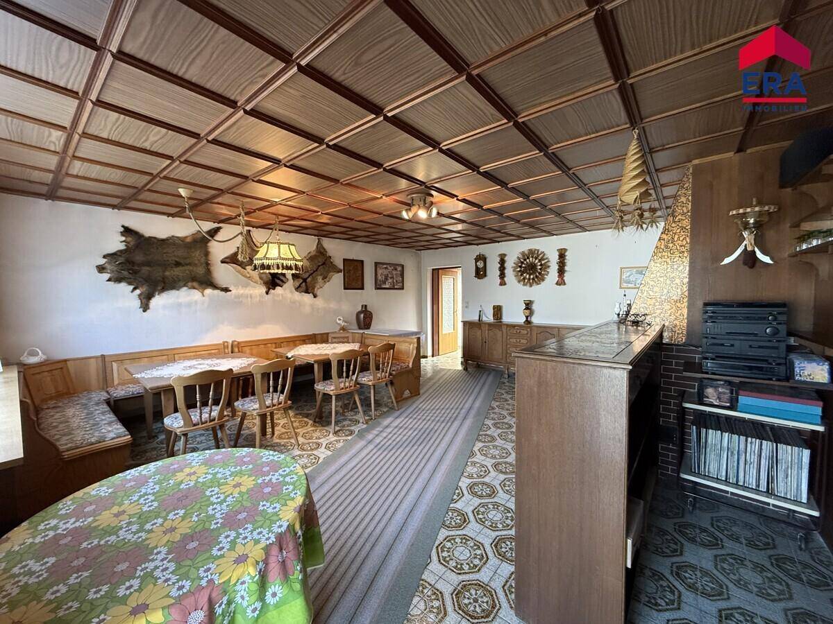 Rustikaler Essbereich mit Holztäfelung, eingebauten Sitzbänken und gemusterter Decke.