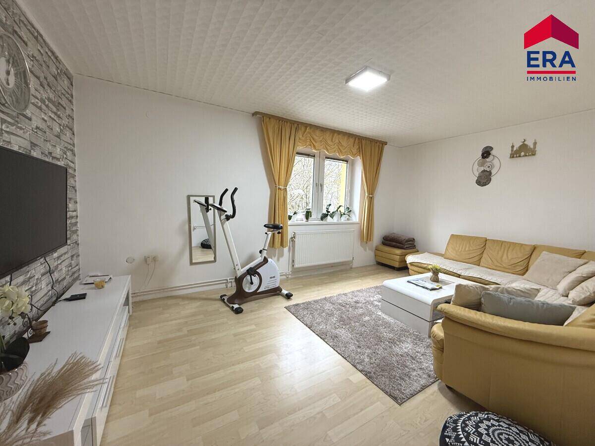 Gemütliches Wohnzimmer mit Sofa, Fernseher und einem Fenster für natürliches Licht.