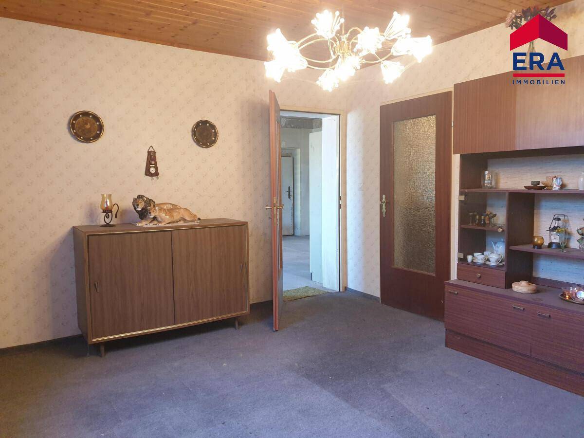 Wohnbereich mit Holzdecke, traditionellen Möbeln und Zugang zu weiteren Räumen.