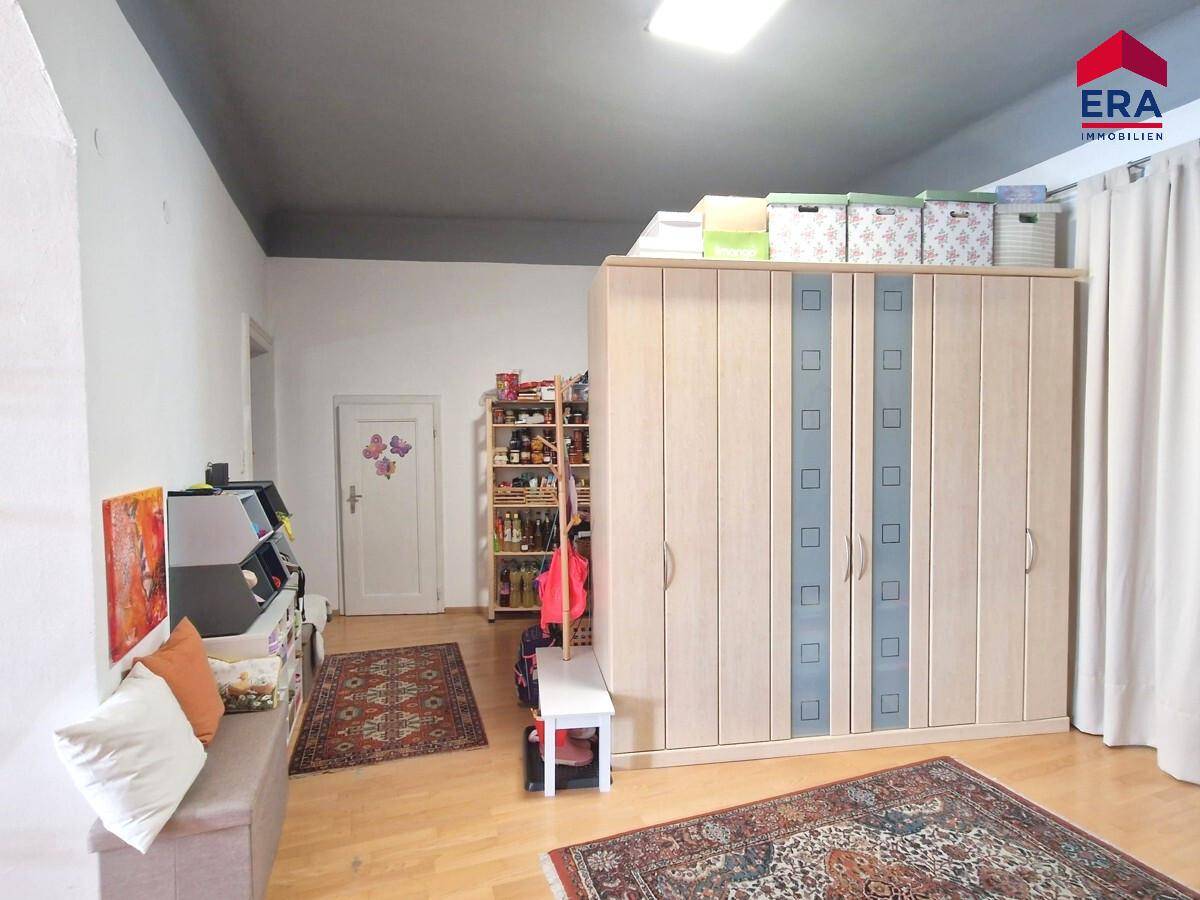 Schlafzimmer mit Holzparkett, großem Kleiderschrank und Teppichen, gemütlich eingerichtet.