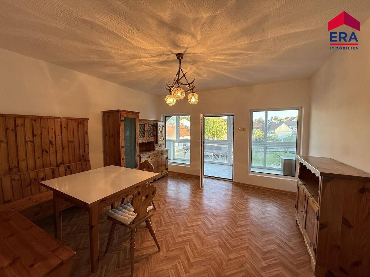 Geräumiger Wohn-Essbereich mit traditionellen Holzmöbeln, Parkettboden und Zugang zum Balkon.