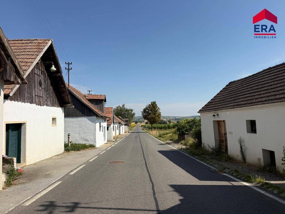 Ländliche Straße mit traditionellen Gebäuden und weitem Blick über die Landschaft.