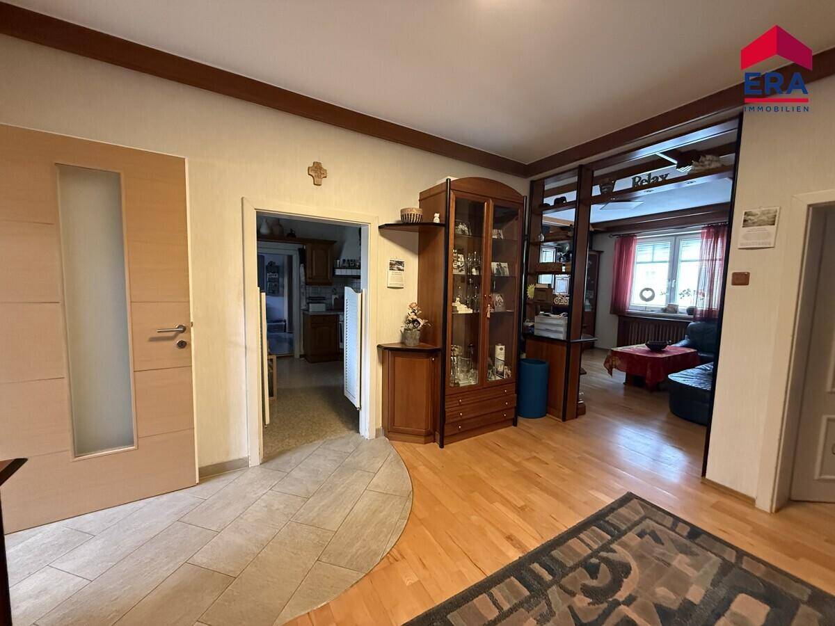 Gangbereich mit Holzboden, Vitrine und Blick in angrenzende Zimmer.