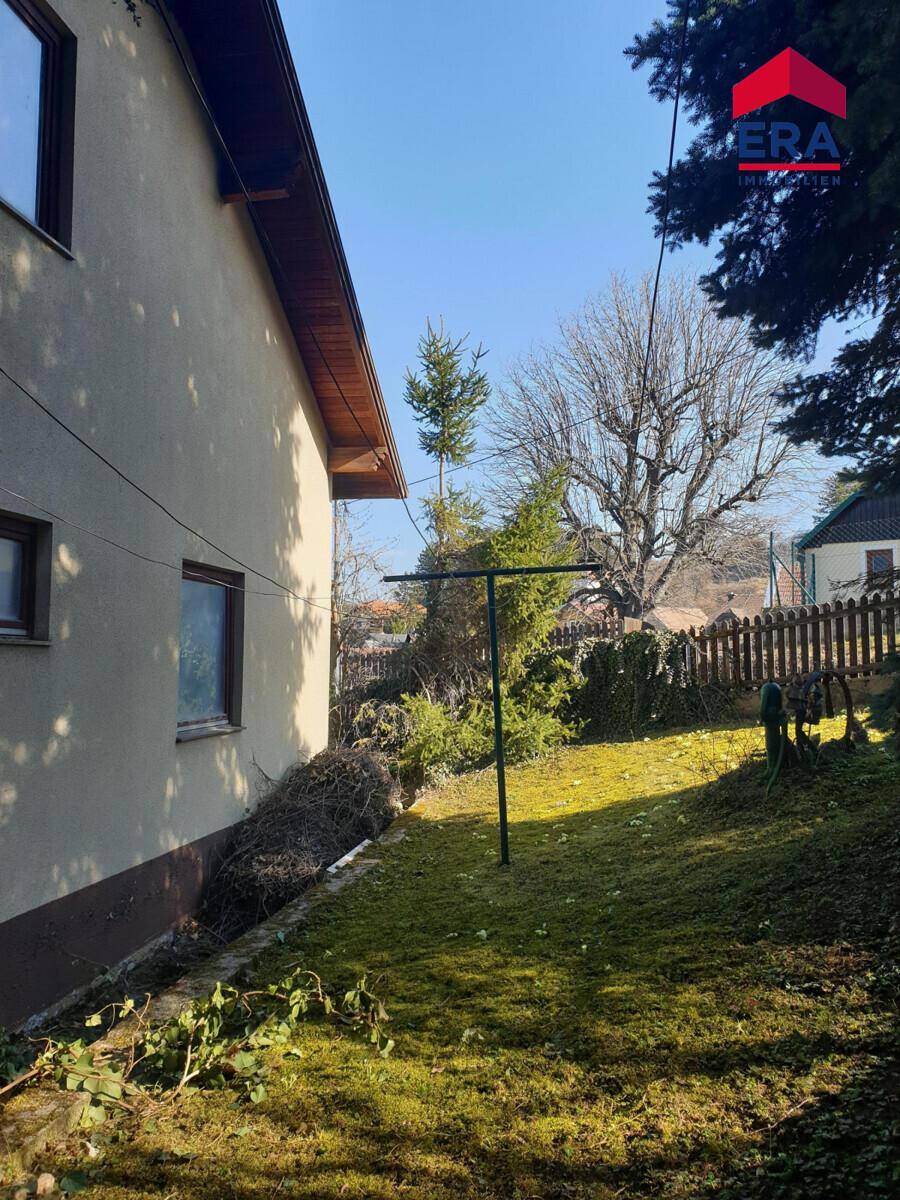 Seitlicher Blick auf das Haus mit einem sonnigen, leicht abfallenden Gartenbereich und Wäscheleine.