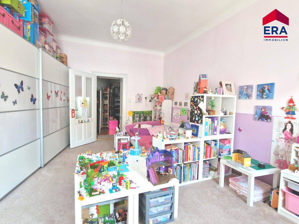 Helles Kinderzimmer mit Teppichboden, Spielbereichen und Stauraum, liebevoll gestaltet.
