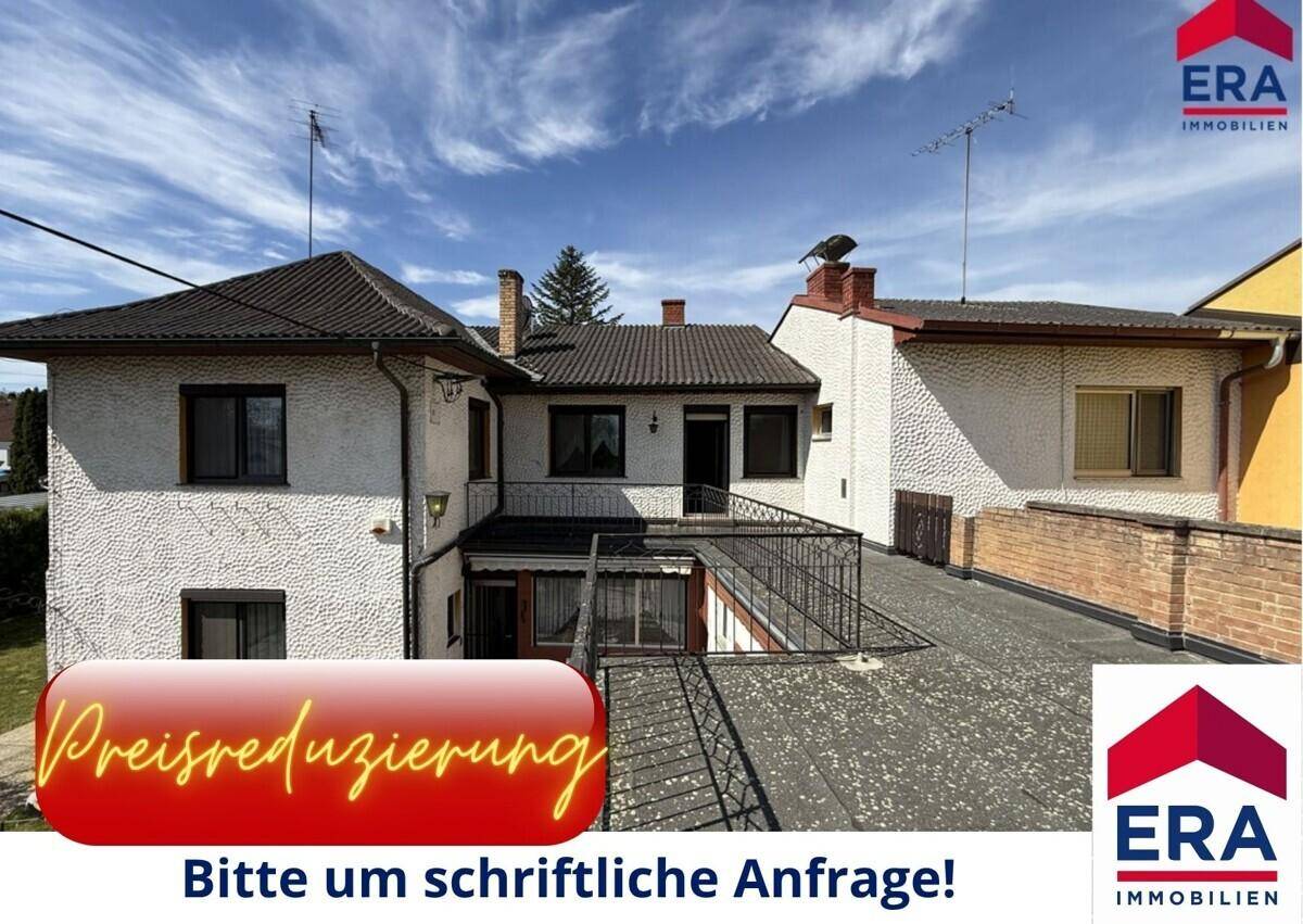Das Haus präsentiert sich mit einer strukturierten Fassade, einem Satteldach und einem Flachdachbereich über einer Terrasse.
