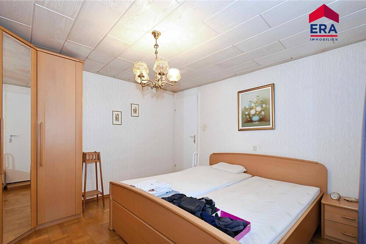 Schlafzimmer mit Doppelbett, Holzpaneeldecke und Kleiderschrank.