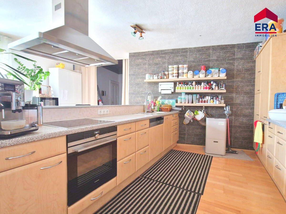 Moderne Küche mit Holzfronten, integrierten Geräten und einer Dunstabzugshaube.