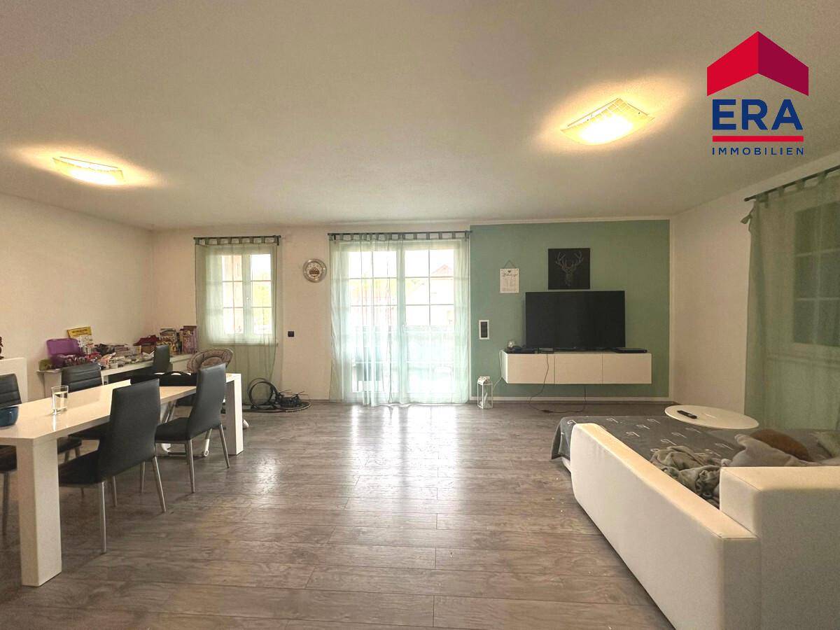 Helles Wohn- und Esszimmer mit modernem Bodenbelag und Zugang zur Terrasse.