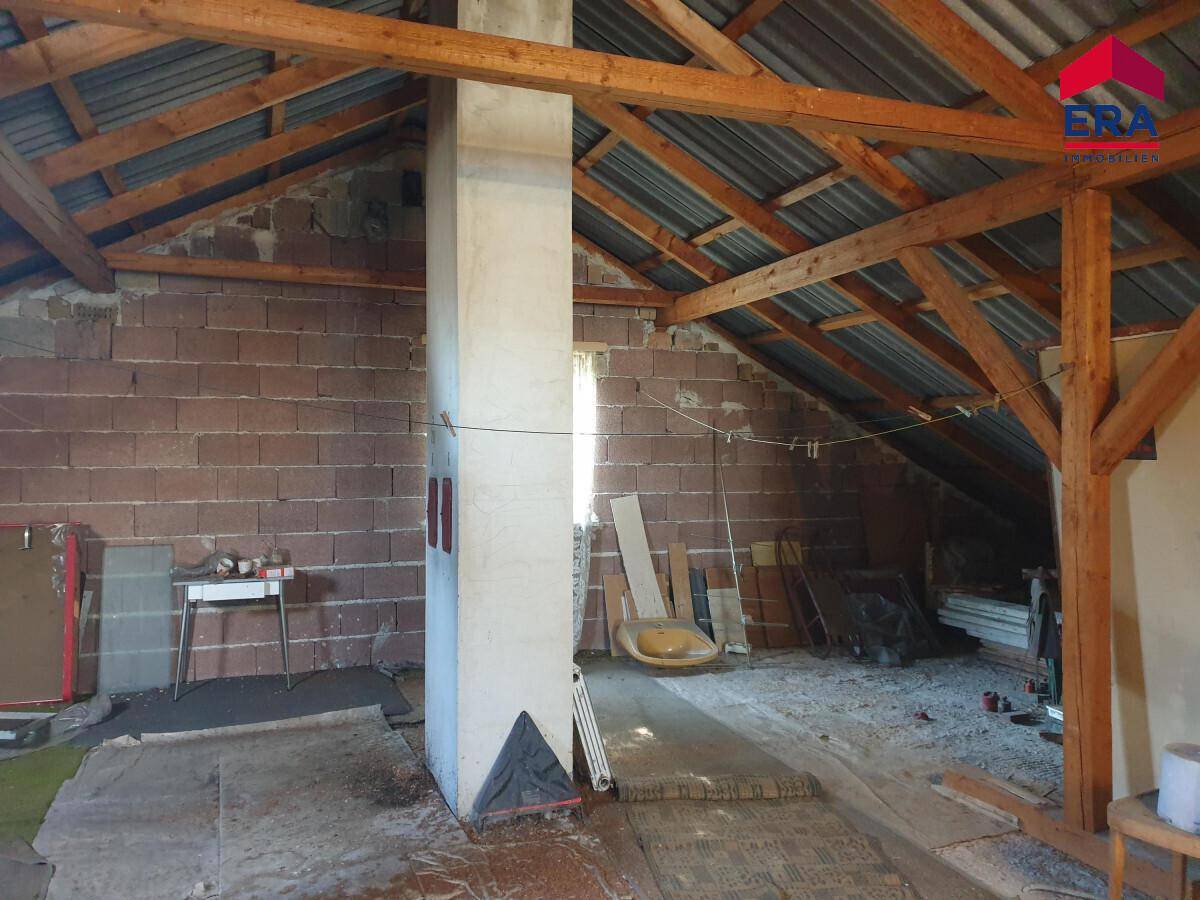 Dachboden mit sichtbaren Holzbalken, Ziegelwänden und viel Stauraum.