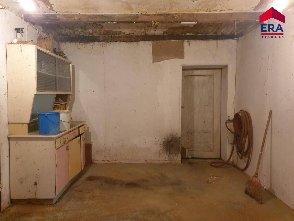 Kellerraum mit einfacher Ausstattung, Waschbecken und Lagerfläche.